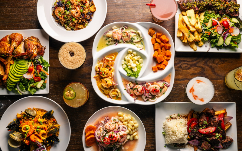 A table covered in Maura's dishes seen from above, with pollo, ceviche, chaufa and salads