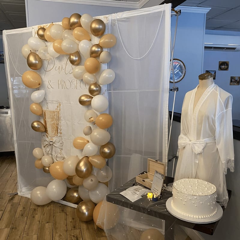 A balloon backdrop and a white cake for a bridal party
