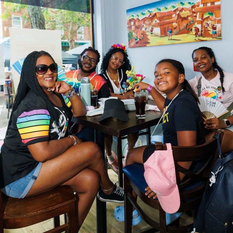 A group of friends at a table with a bright mural behind them