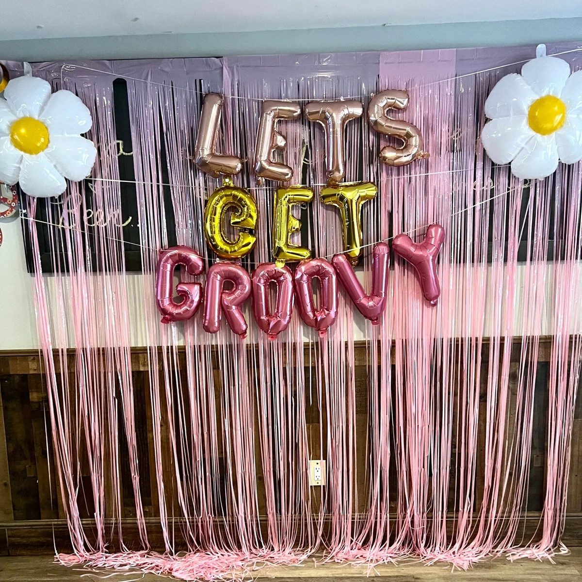 The party room decorated with balloons and a pink fringe backdrop
