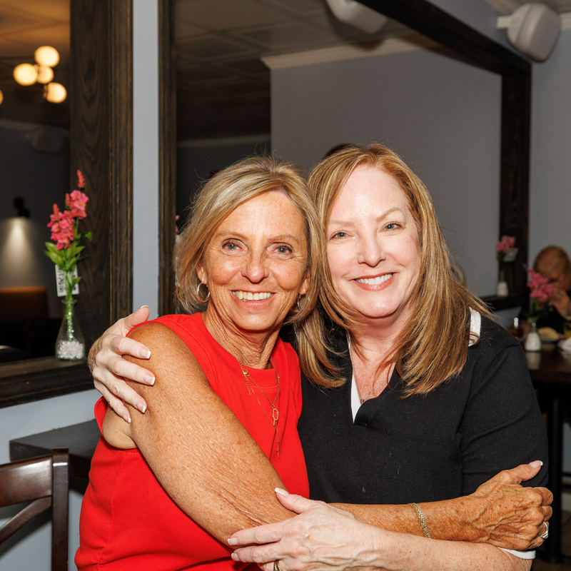 Two guests hugging and smiling in the dining room